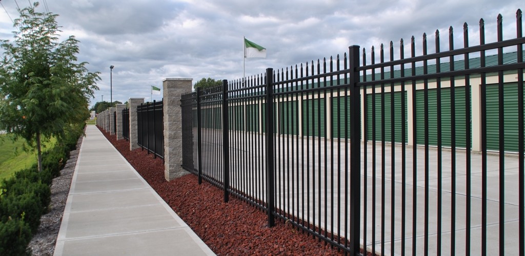 The site features a black aluminum picket fence with masonry pillars about every 30 feet.