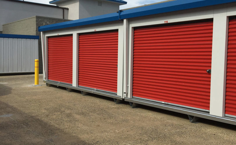 Micro units are used on a self-storage site to take advantage of paved areas outside. These micro units have patriot red doors and royal blue trim. 