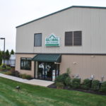 This self-storage site has multi story buildings with gable roofs. The buildings are classic beige, light stone with evergreen trim, roof and over hang.