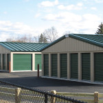 Classic beige self-storage buildings with evergreen doors. Roofs are evergreen standing seam with a 3:12 pitch.