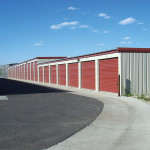 Slate gray self-storage buildings with cedar red doors and trim. 