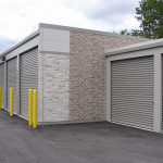 One-story classic beige self-storage buildings with shale doors. Exterior facade Nichiha brand fiber cement products.