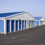 One-story 3:12 pitch roof, iced white self-storage buildings with royal blue doors.
