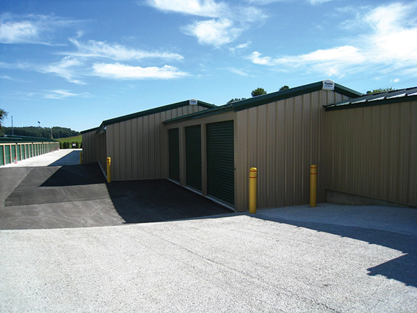 Classic beige self-storage buildings with evergreen doors, trim and roof. Features standing seam roofs with 3:12 pitch.