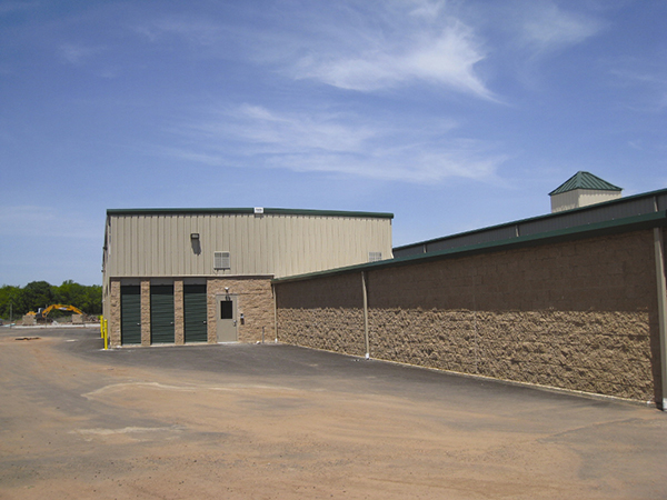 One and two-story classic beige self-storage buildings with evergreen doors and block perimeter.