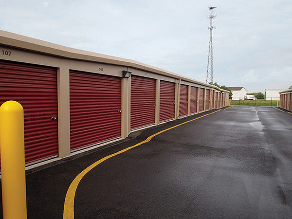 Classic beige self-storage buildings with rolling steps and cedar red doors. 