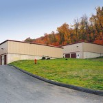 This self-storage facility has two story into a hill classic beige buildings with cedar red doors and trim.